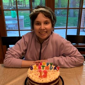girl smiling behind a 13th birthday cake